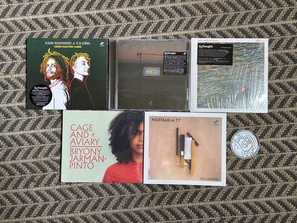 Five new CDs and a sticker. 
The CDs are:
“Gnawa Electric Laune” by Rabii Harnoune & V B Kühl
“Magnetica” by Quantic
“Mirage” by Anchorsong
“Cage and Aviary” by Bryant Jarman-Pinto
“The Garden” by Nostalgia 77