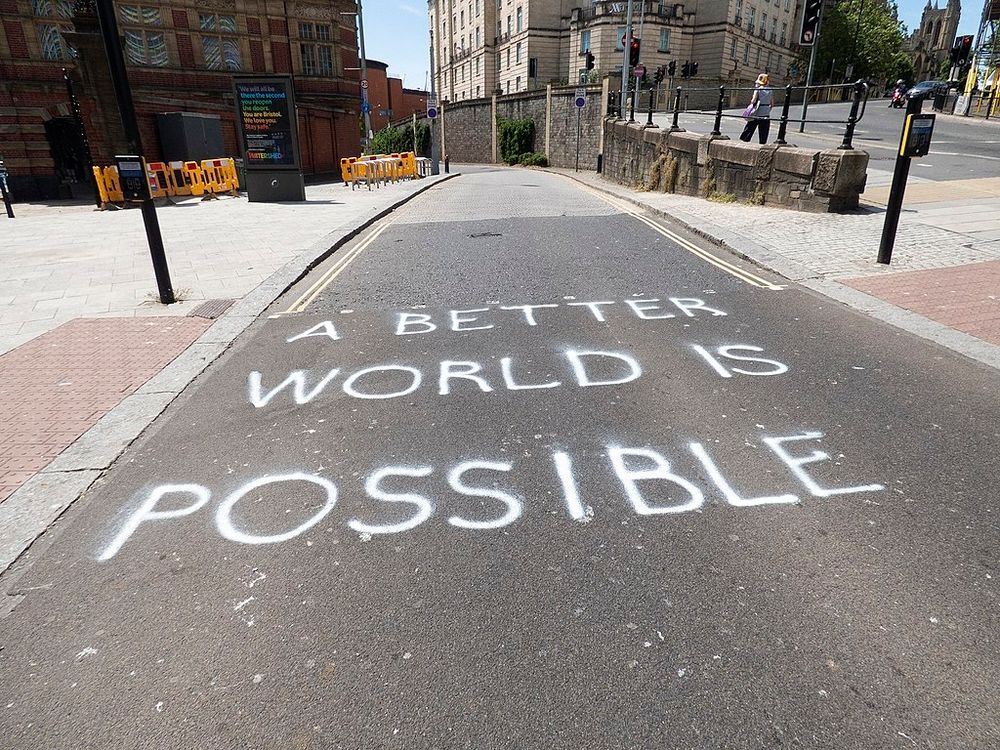 A street painted with the words A BETTER WORLD IS POSSIBLE