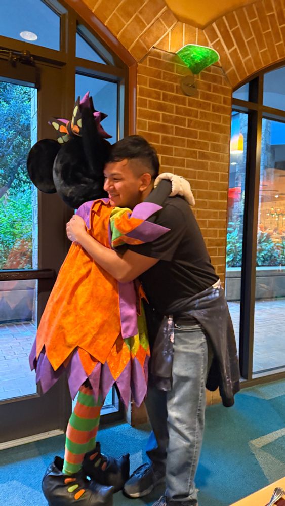 Picture of Peter hugging Minnie Mouse, who is dressed witchy