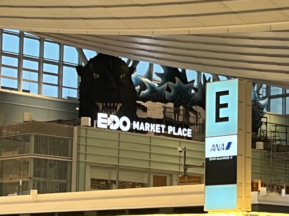 Photo de l’aéroport de tokyo avec un gros godzilla qui surveille les passagers 