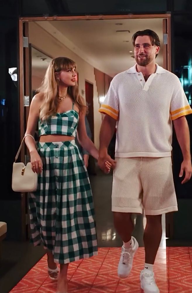 Taylor Swift and Travis Kelce smiling and holding hands. 