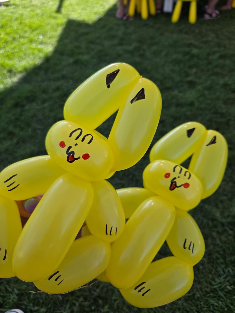 Das Bild zeigt zwei gelbe Luftballontiere, die wie Hasen geformt sind. Die Hasen haben mit einem schwarzen Stift aufgemalte Augen, Nasen und Pfoten. 