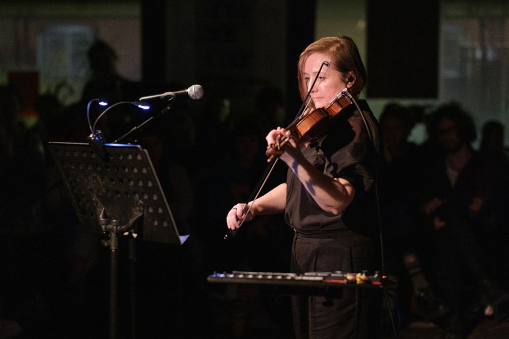 Ellie Wilson with violin and electronic keypad, playing into a microphone