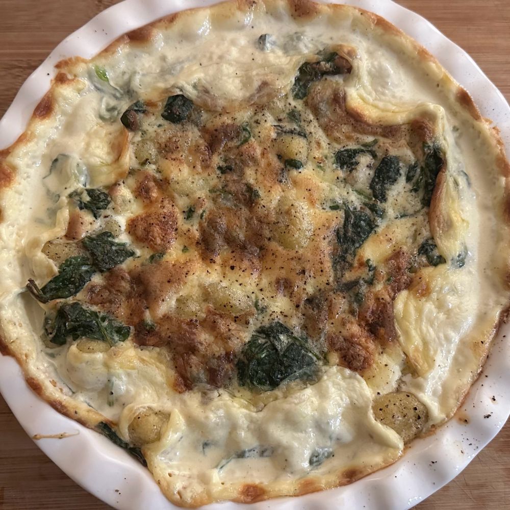 Gnocchi with spinach and dolcelatte bubbling in a white dish just out of the oven.