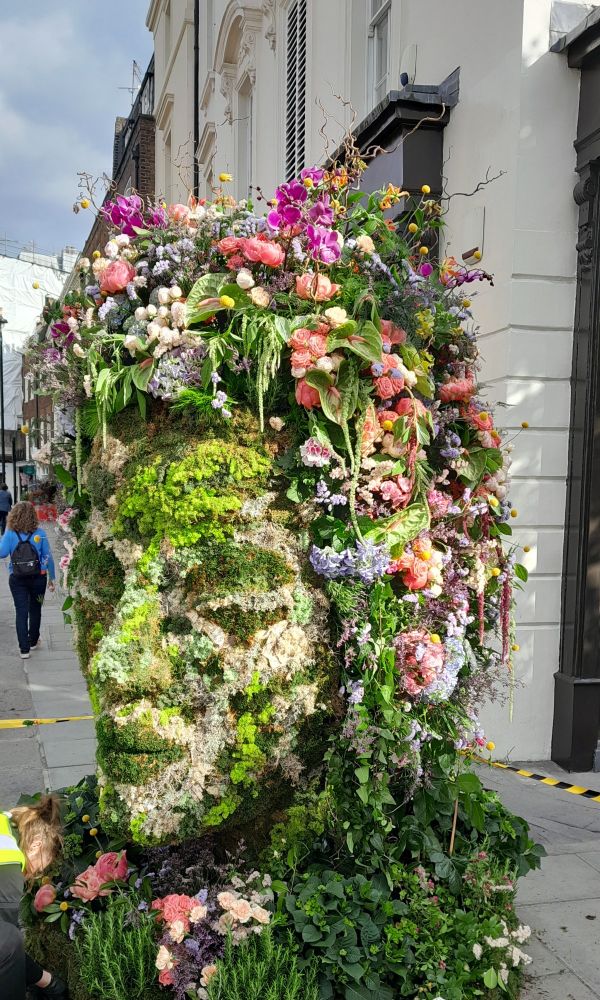 A large human face made of different colour flowers 