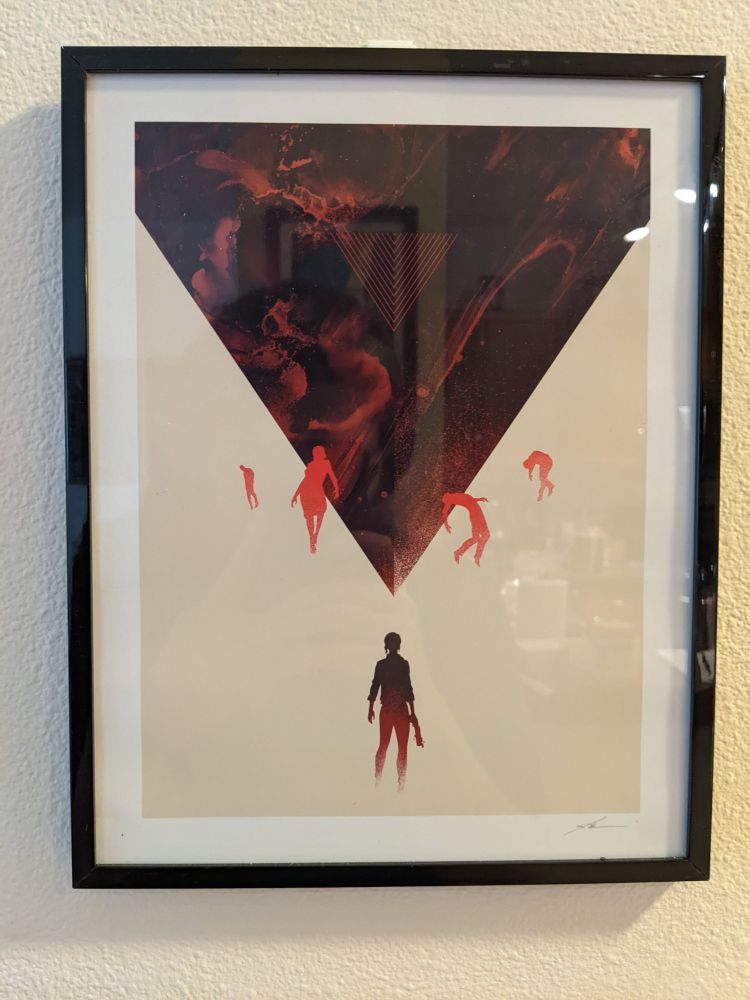 An inverted pyramid covered in an oily red substance, several figures float around it, contorted silhoutted in red and a woman stands, her back to us, facing it.