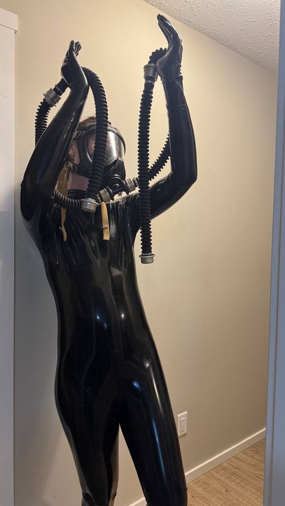 Me in a latex catsuit and gas mask, holding the air hoses above my head. 
