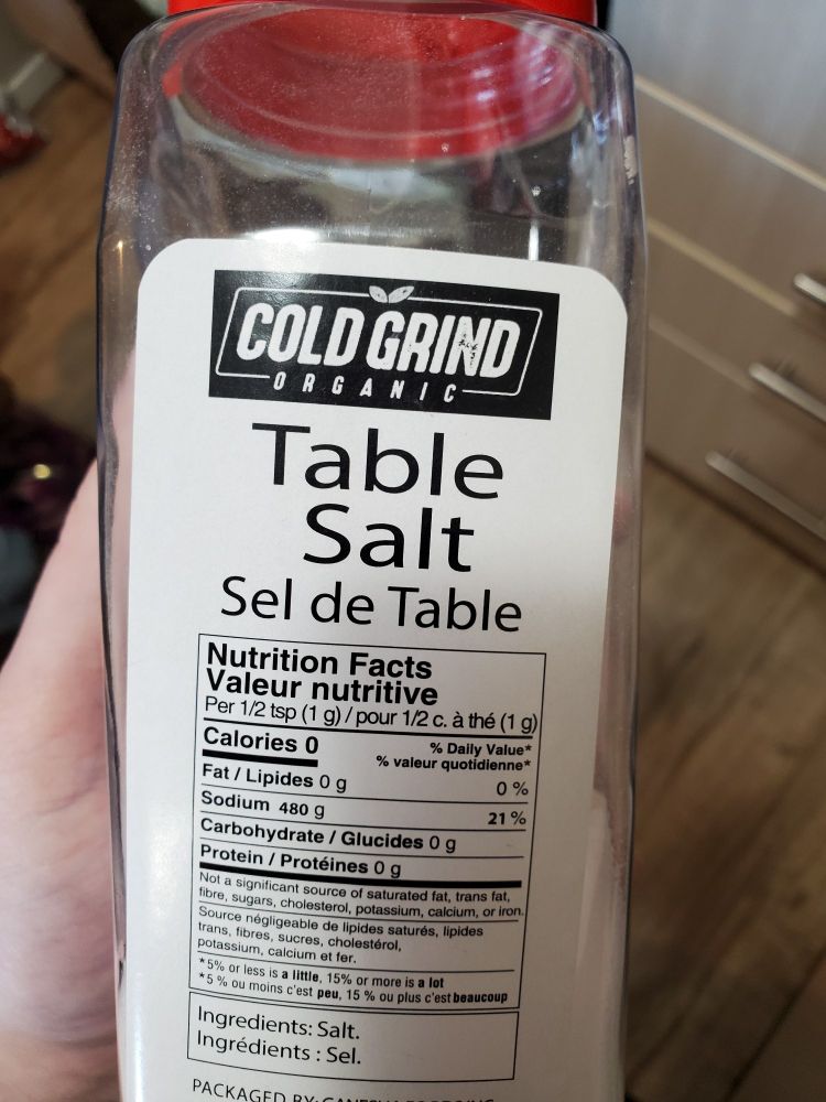 A large bottle of table salt. The brand name is "Cold Grind Organic". The nutritional facts table indicates that there is 480g of sodium for every gram of salt.