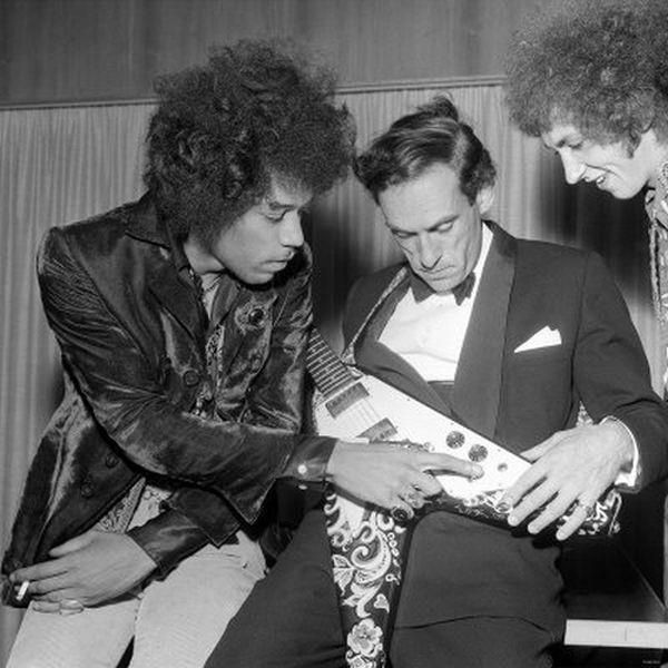 A black and white photograph of disgraced Liberal Party leader Jeremy Thorpe inspecting Jimi Hendrix's rather beautiful Flying V guitar (with a floral pattern on the body), while Hendrix explains the volume and tone controls.