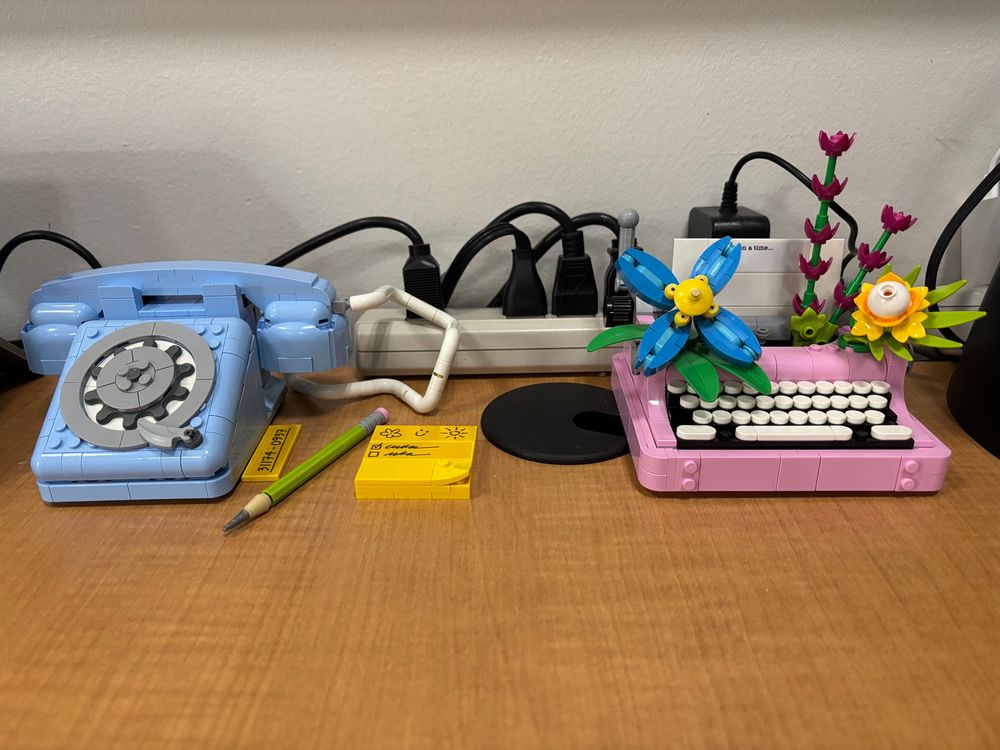 A lego telephone, pencil and message pad on one side and the mini lego typewriter with flowers on the other side
