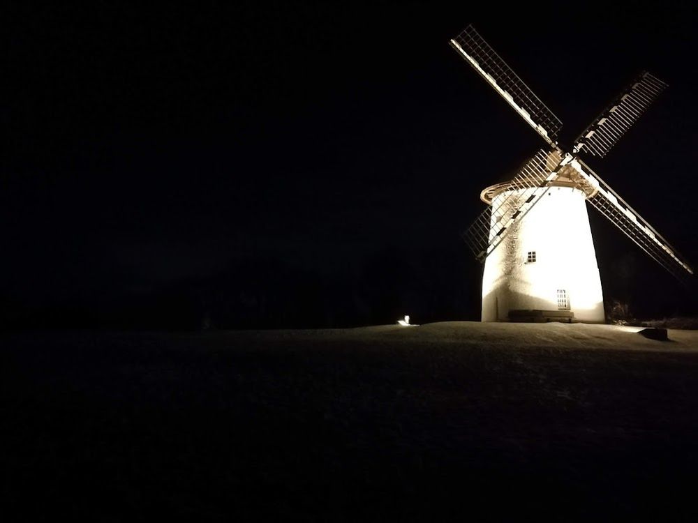 Aufnahme einer beleuchteten Mühle bei Nacht.