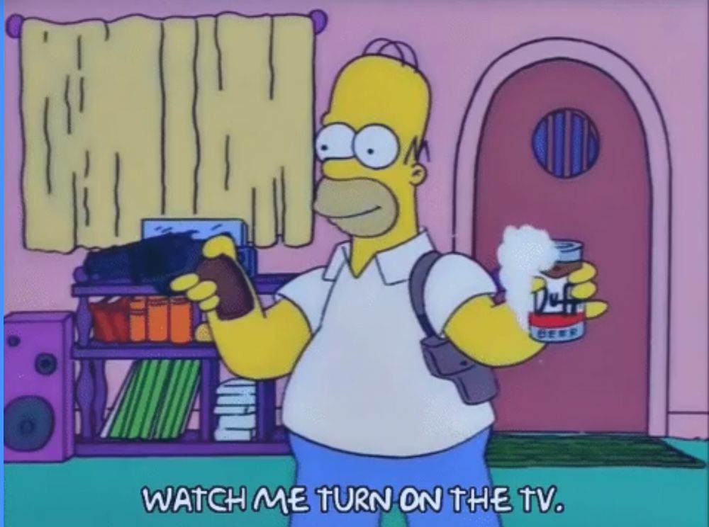 Homer Simpson holding a beer and a handgun saying “watch me turn on the tv”