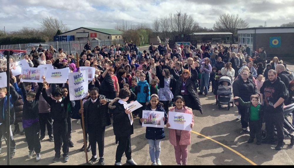A photo showing a playground full of people doing the Big Lent Walk. Some are holding signs. 