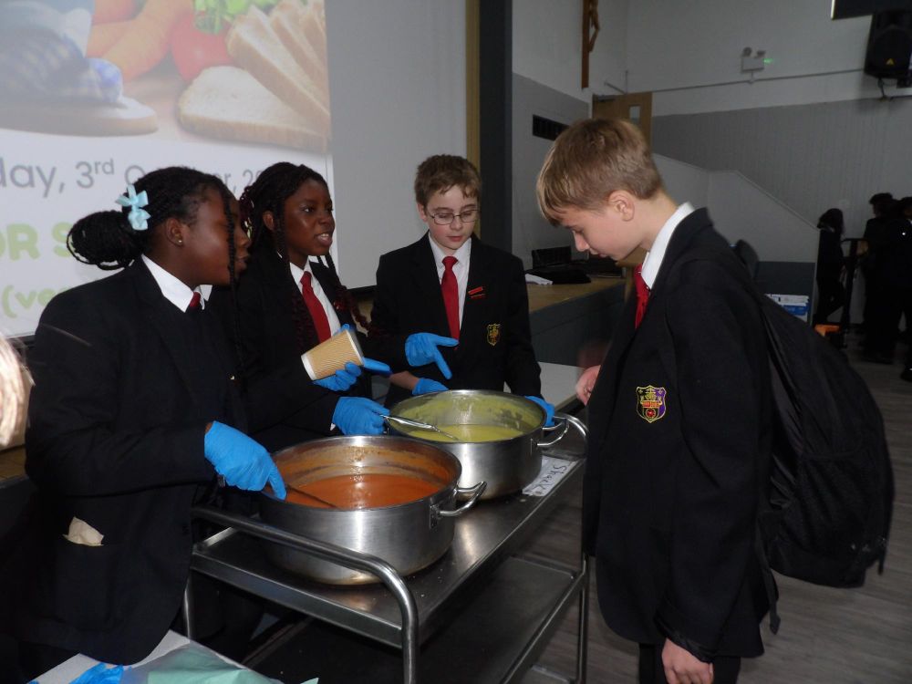 School students serving soup from large bowls. 