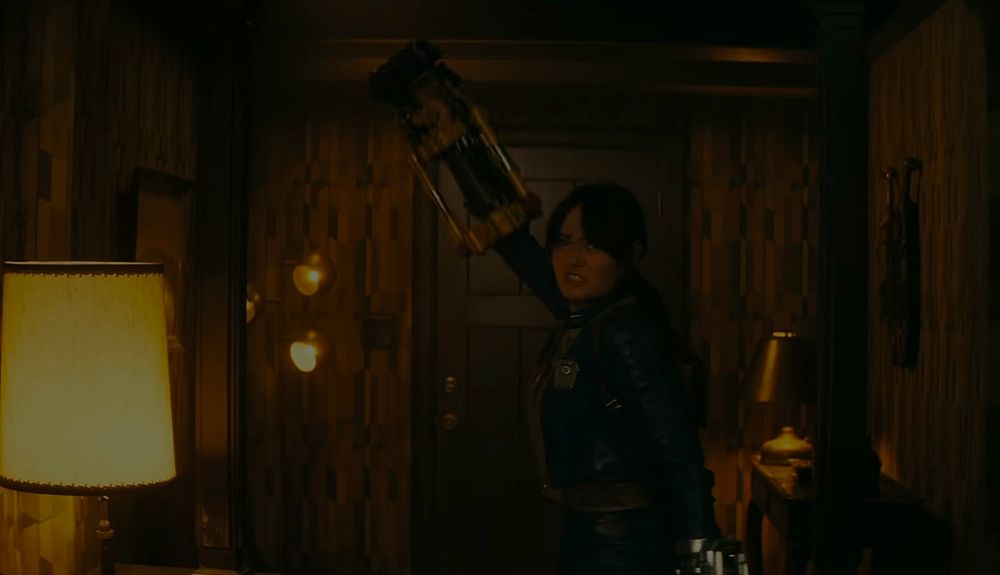 Lucy from the show Fallout readying a power fist in a yellow-y room.