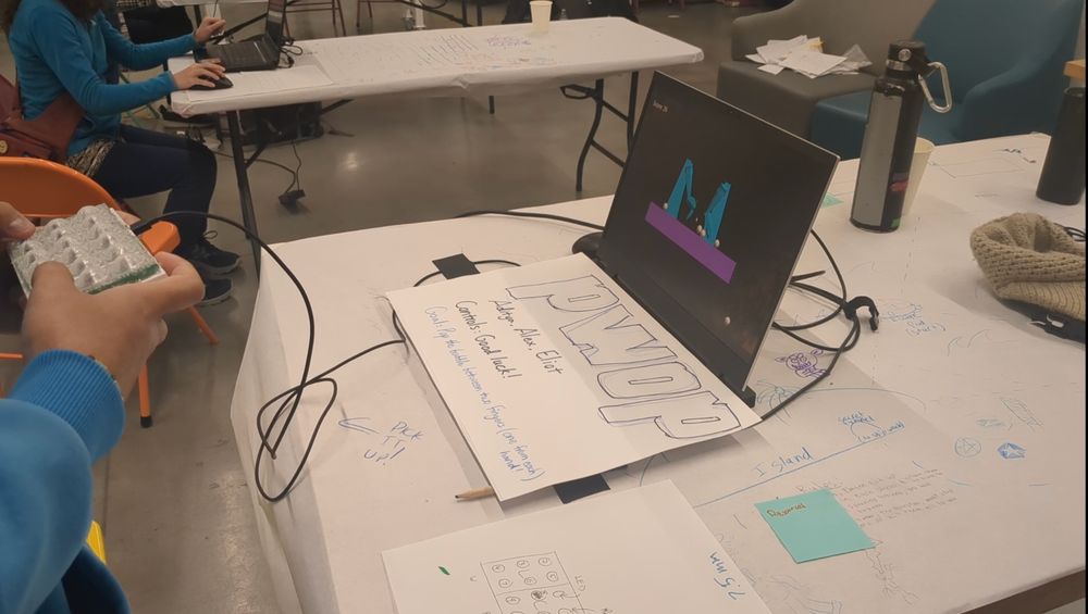 A laptop running PWOP has the keyboard covered with a hand-drawn PWOP sign. It's connected to a phone-sized box with 18 translucent plastic bubbles on top reminiscent of bubble wrap.