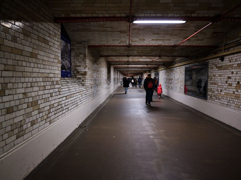 Photo of people walking in the tunnel in South Kensington to the Museums. There are various people all walking away from the camera towards the stretch of museums.