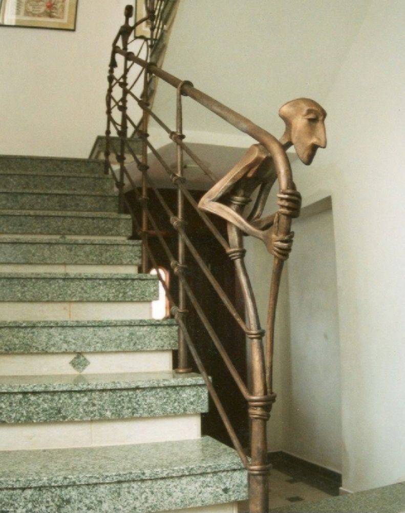 A unique staircase railing features an artistic metal design, resembling a figure, alongside polished green granite steps.