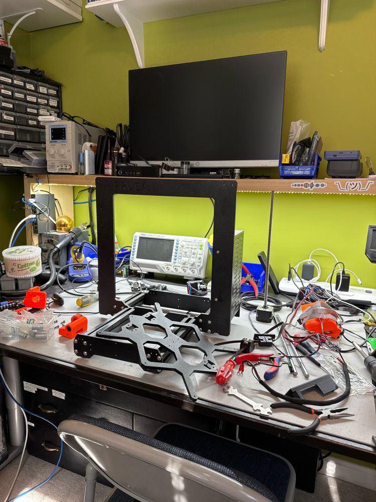 A messy work workbench featuring a 3d print taken apart for an upgrade. 