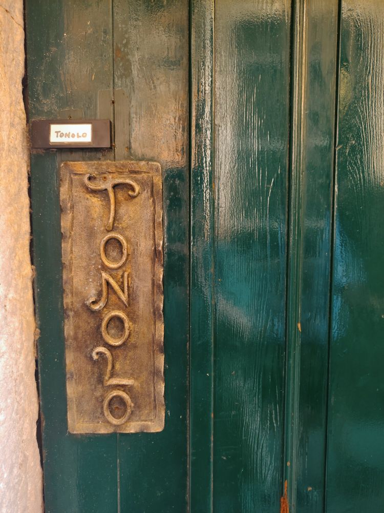 Porte arrière de la pâtisserie Tonolo, avec poignée en bronze ornée du nom de la pâtisserie en belles lettres stylisées