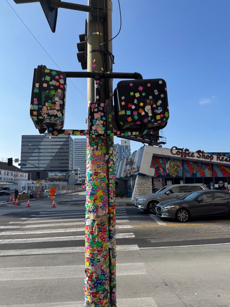 Traffic signal outside of Los Angeles MOCA, covered in museum admission stickers.