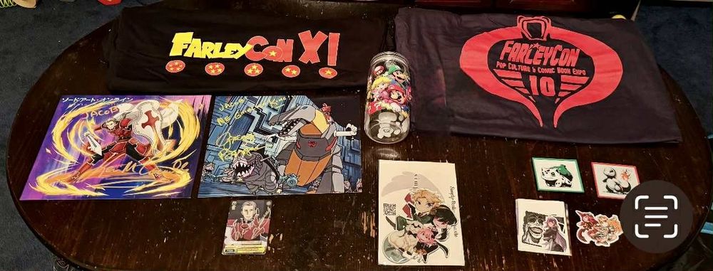 Two farleycon t shirts, two autographed prints, a mario jar, spy x family standee, two pokemon magnets, solo leveling and xenoblade chronicles 2 stickers
