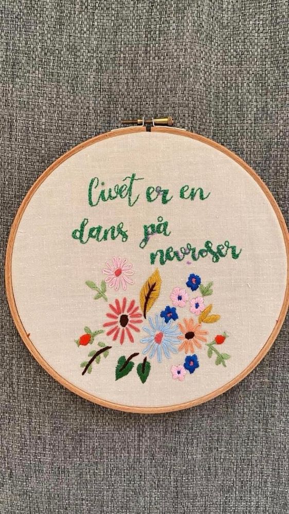 Bilde av et broderi med teksten 'livet er en dans på nevroser' med blomster i flere farger under. 