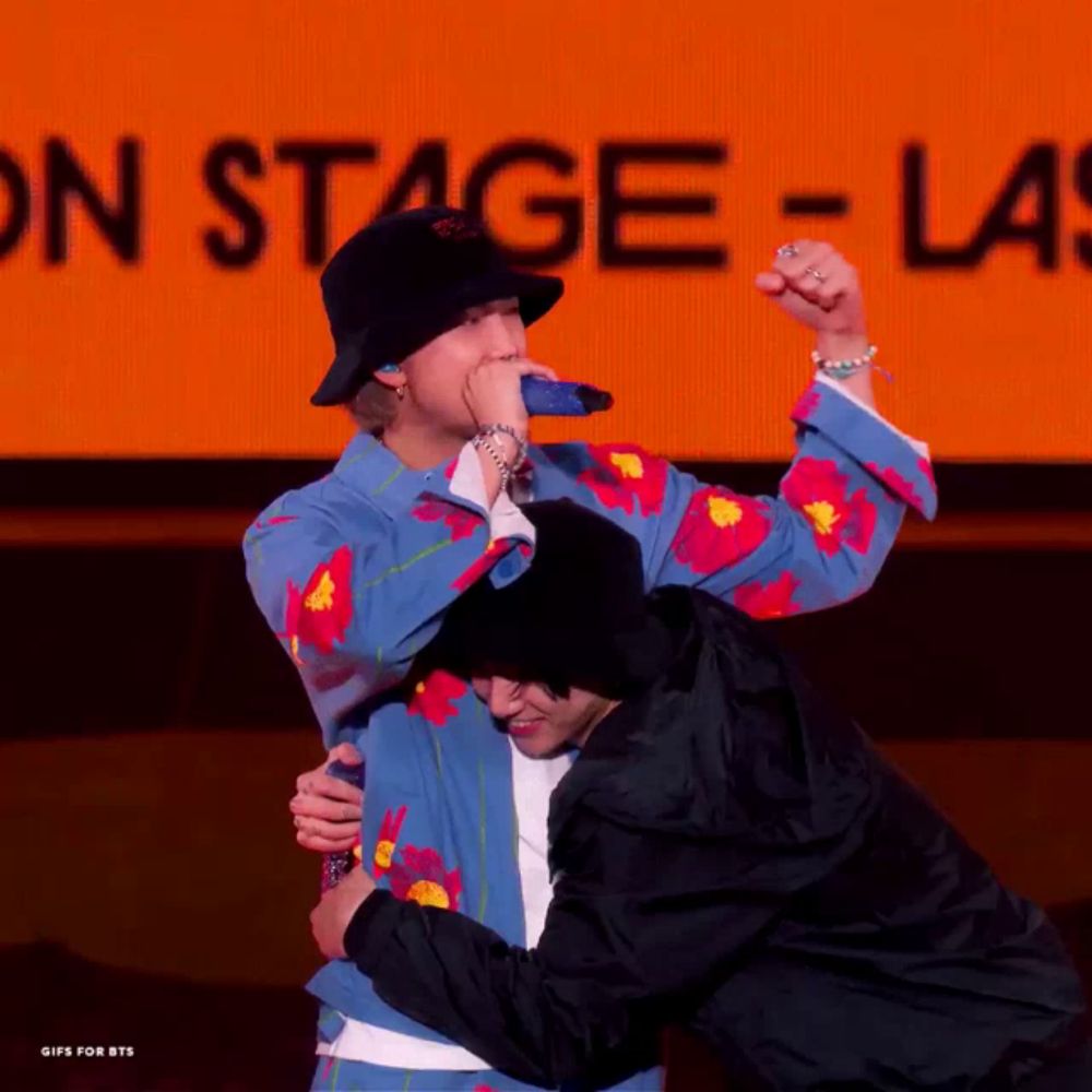 two men hugging each other in front of a sign that says on stage