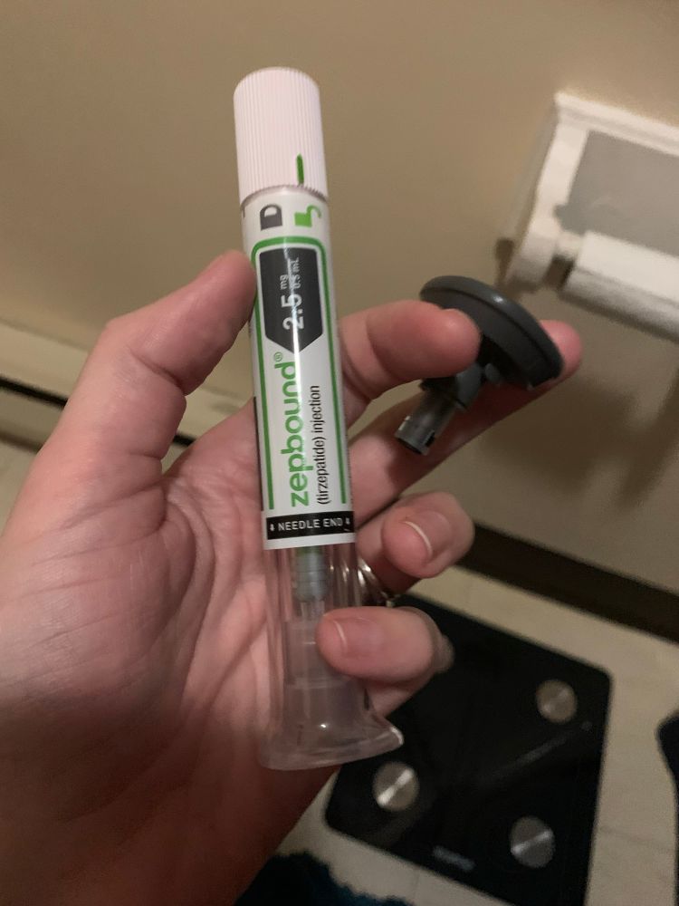 A hand holding a recently used Zepbound 2.5mg auto injector pen 