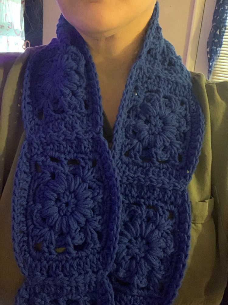 Me modeling the blue flower granny square scarf showing the length 