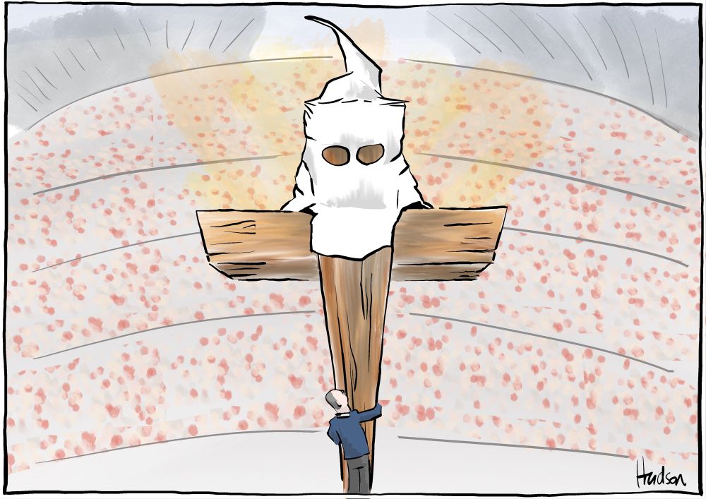 In a stadium full of people somewhere, a man is hugging a huge wooden crucifix and looking reverently skyward. The crucifix is adorned with the headwear of the ku klux klan, and a glow Emirates from behind it. 