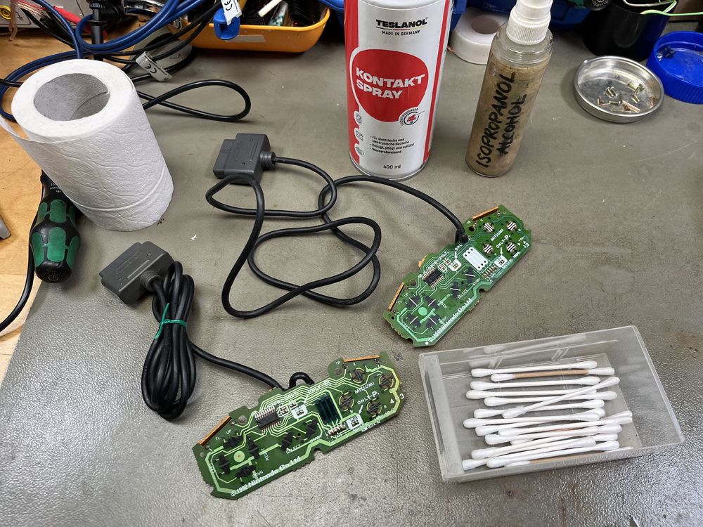 The Mitsumi circuit boards from the two controllers on my workbench, cleaned with alcohol and contact cleaner. Q-tips, tissues, IPA and contact cleaner are sitting next to the PCBs.