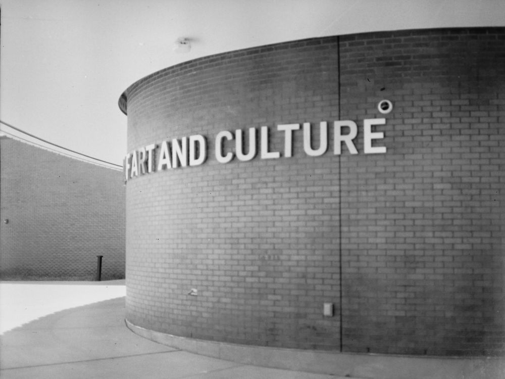 black and white film photo of a curved exterior brick wall of a museum, viewed from an angle so that it reads "fart and culture"