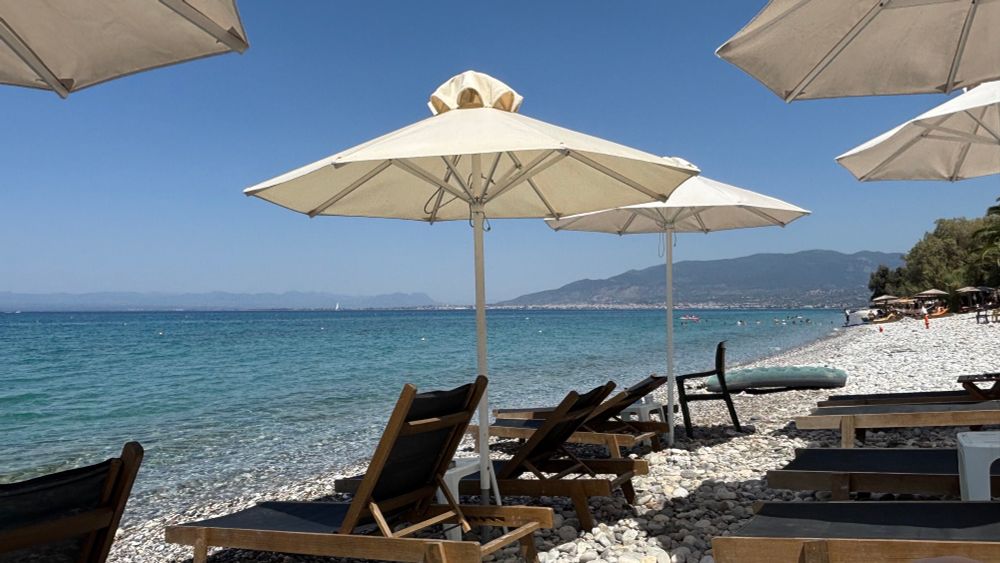 A beautiful, white pebble beach near Kalamata, Greece. Lounge chairs and beach umbrellas wait for locals and those vacationing here to arrive. For the price of a frappe (coffee) you can stay all day.