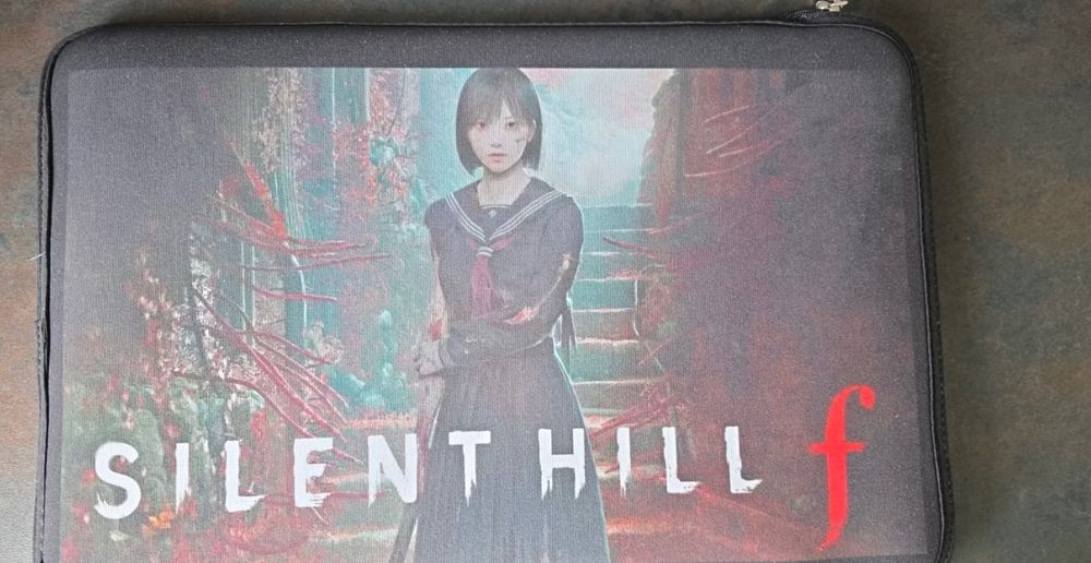Laptop sleeve with artwork from "SILENT HILL f". The design features a young woman in a dark school uniform standing in front of a stairway with an eerie, surreal background filled with red and green organic, tendril-like shapes. The title "SILENT HILL" is written in large white letters along the bottom, and a distinctive red lowercase "f" stands at the end of the title. The overall atmosphere of the image is unsettling and mysterious.
