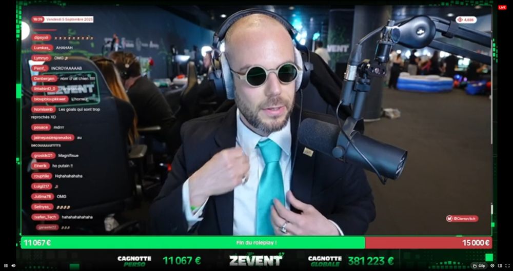 Clément Viktorovitch au Zevent, dans un cosplay "patron de droite" avec un costard, une cravate bleue immonde et des petites lunettes de soleil rondes. 