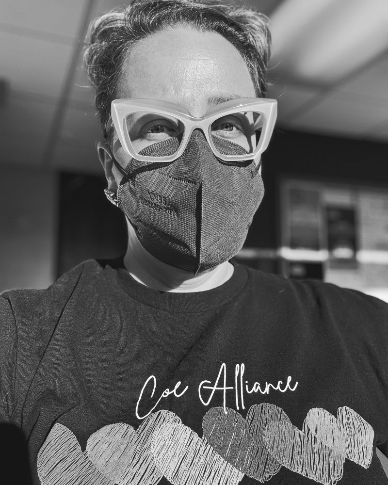 Jen is angry. She is wearing a mask, her glasses and a Coe Alliance tshirt.
