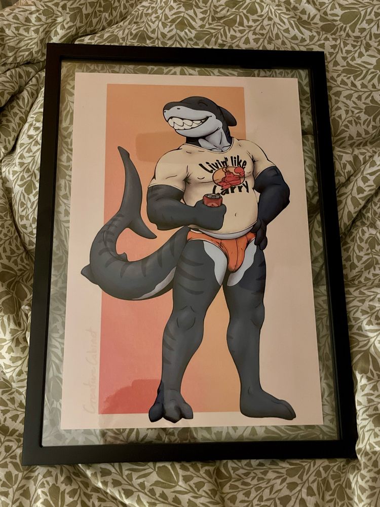 Colored print of a digital drawing of an anthro tiger shark man standing with one hand on his hips and another holding his favorite chili beer. He is wearing only his boxer briefs and a tight t shirt that says “Livin’ like Larry” featuring a picture of Larry the lobster. He is giving a big smile, large muscles, and a big tummy that hangs out of the bottom of his shirt.
