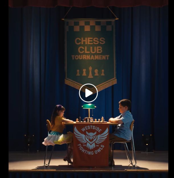 Two children facing each other in a chess tournament