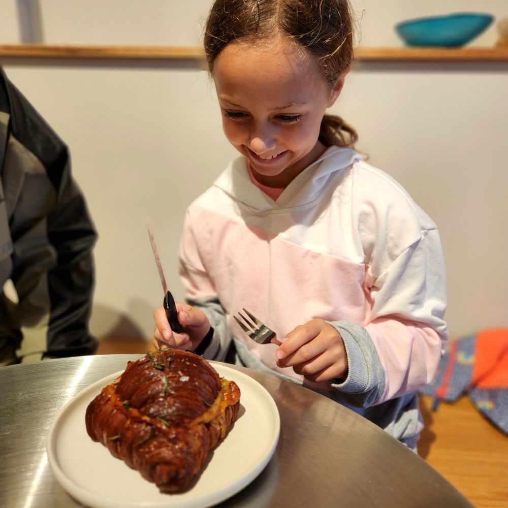 Kid 1 eating a ham and cheese croissant with hot honey and rosemary 