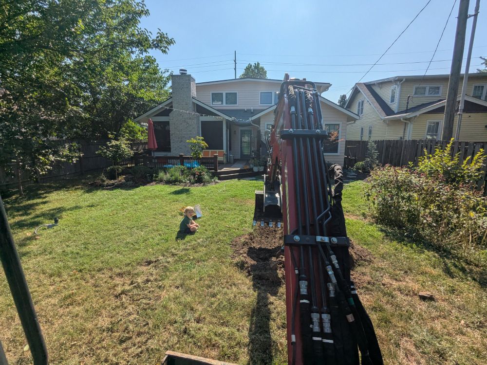 boy sitting next to an excavator 