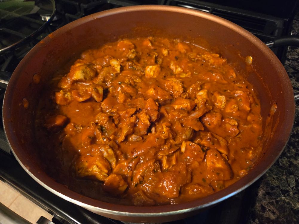 A sauté pan filled with turkey (mixture of dark and breast meat) drenched in Butter Chicken sauce! Colorful,  
mildly spicy, tender and very delicious.