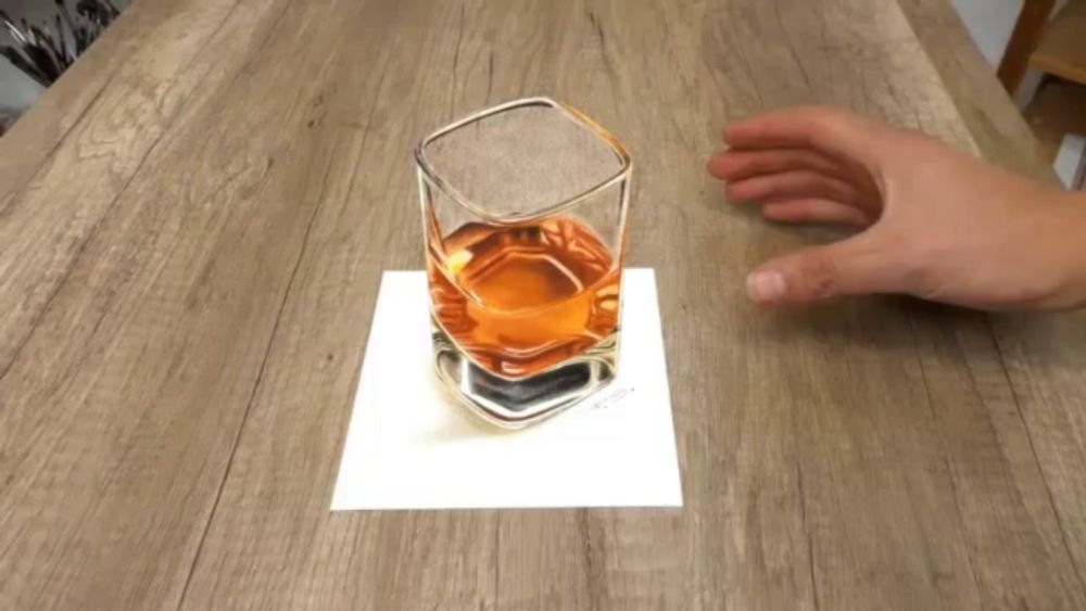 a hand reaches for a glass of whiskey on a wooden table