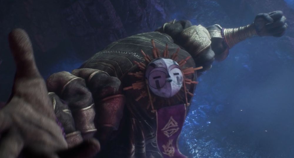 Esquie from Clair Obscur: Expedition 33 reaches up to the sky dramatically. He is a large cuddly looking guy and his face is a wooden mask with straight eyes and mouth, surrounded by a sunburst design.