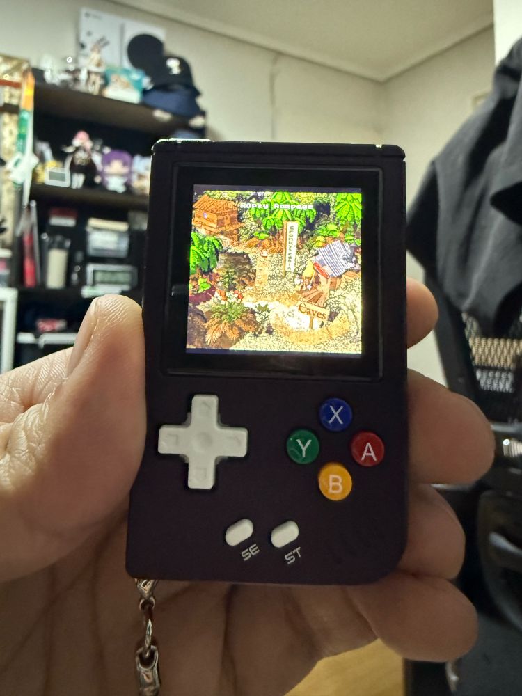 A RG Nano being held by a hand, showing the first part of the first world of Donkey Kong Country.
