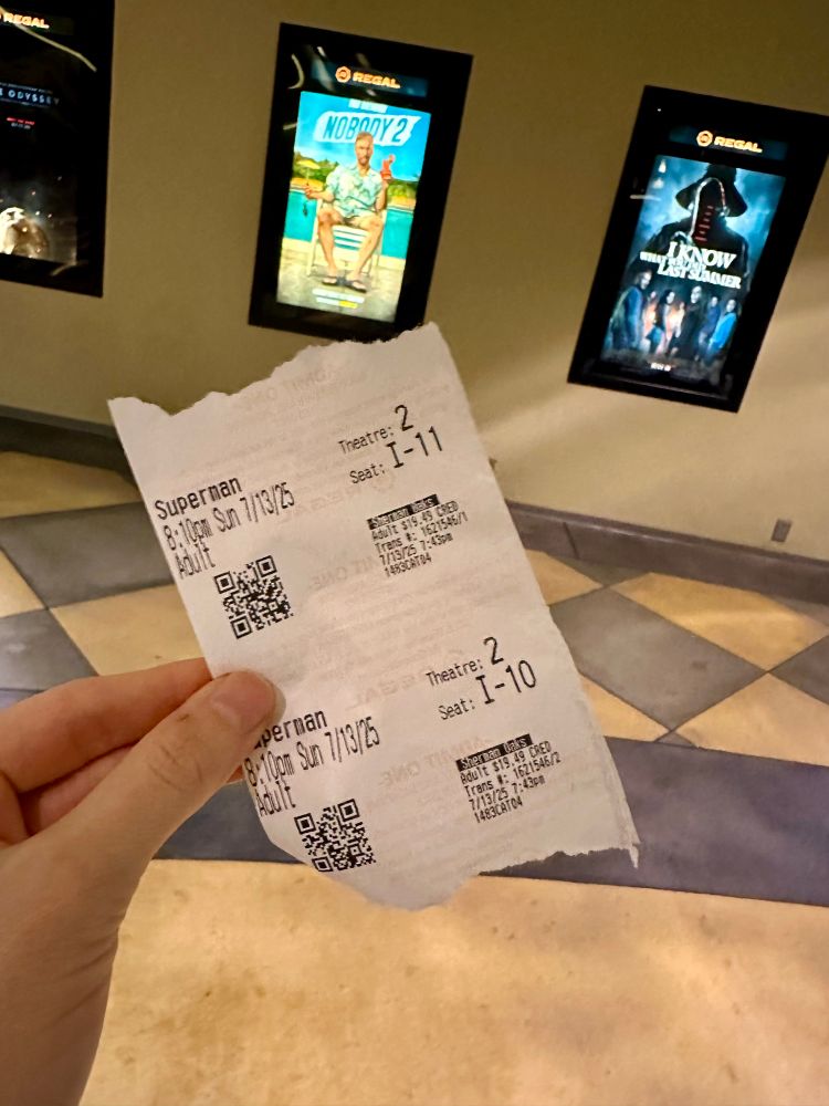 a superman movie ticket, slightly eaten by the ticket dispenser, in my hand