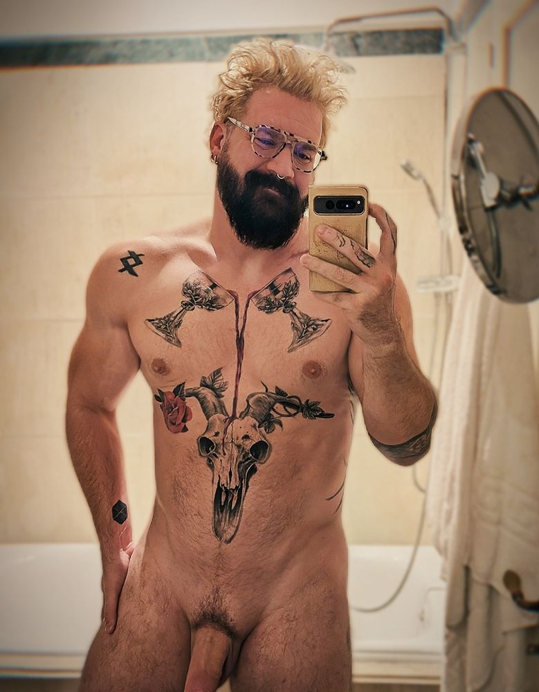 Jason taking a nude selfie in a nice Greek bathroom. They are smiling with messy hair and their cock partially cropped out