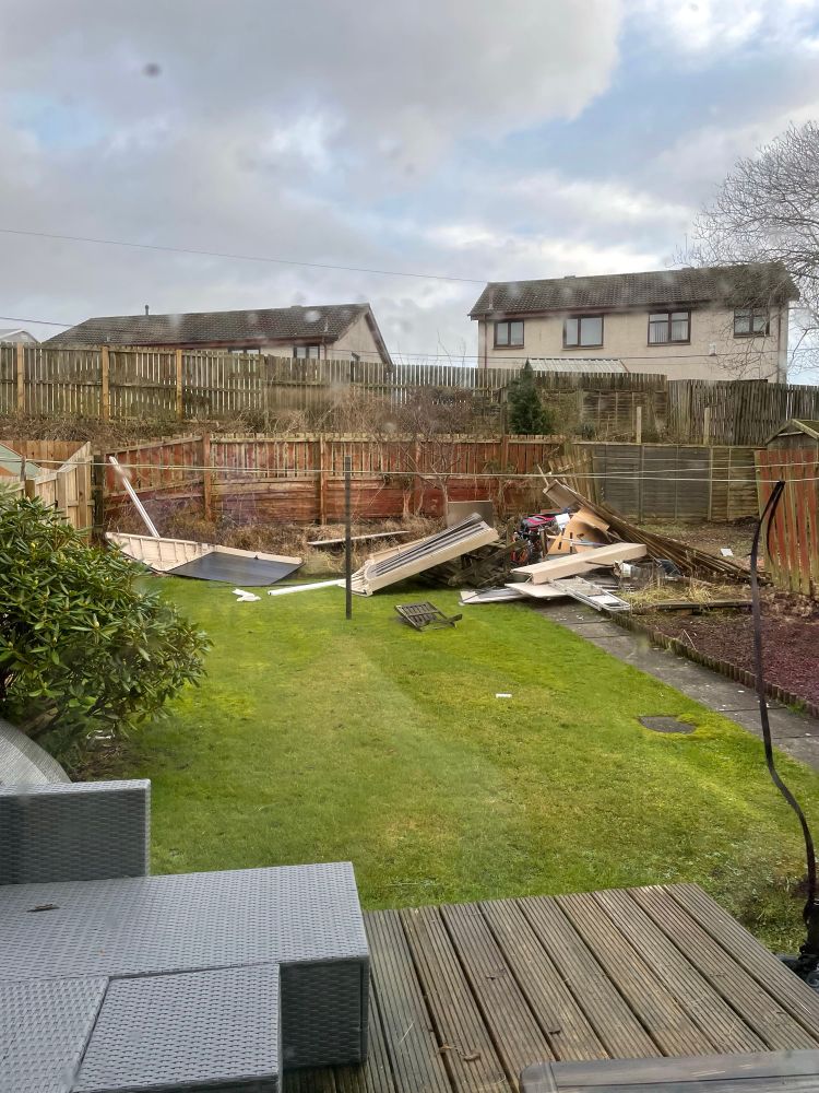 The wind blown remains of a shed are seen strewn across the end of a back garden. Totally destroyed - it doesn’t look like a shed at all. 