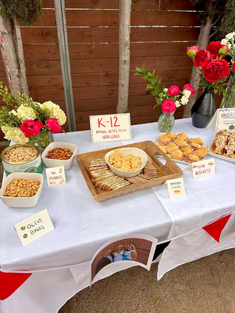 An array of food on a table. A sign reads “K-12: small bites from Virginia.” Dishes include VA peanuts, pimento cheese, and ham biscuits 