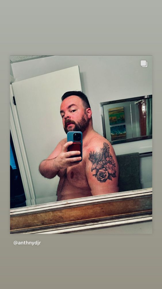 Mirror pic of a naked man in bathroom showing off new tattoo of an eagle and flowers on upper arm